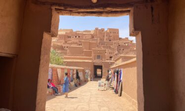 15 Days Morocco Desert Tour from marrakech ,A sweeping desert panorama: A wide-angle view of the golden sand dunes of Erg Chebbi during sunset on a 15-day Morocco desert tour from Marrakech. A camel caravan silhouette: Silhouette of a camel trek against a vibrant orange and purple sunset sky in the Sahara Desert near Merzouga. Atlas Mountains view: Scenic drive through the winding roads and dramatic landscapes of the High Atlas Mountains on a tour from Marrakech to the desert. Ait Benhaddou aerial shot: Ancient Ait Benhaddou kasbah, a UNESCO World Heritage site, built from red clay and overlooking the Ounila River valley. Dades Gorge scenery: View of the stunning switchback roads and unique rock formations in the Dades Gorge, known as the Monkey Fingers, on a Morocco tour.,Berber village visit: A local Berber woman weaving a traditional carpet in a small village in the Atlas Mountains during a cultural tour. Traditional tagine meal: A delicious, steaming Moroccan tagine with meat, prunes, and almonds, served as part of an all-inclusive desert tour. Fes medina tannery: Overhead view of the ancient Chouara Tannery in Fes, showing the iconic dye pits from a Morocco cultural tour. Local guide with group: A knowledgeable local tour guide explaining the history of a ksar to a small group of travelers on a Morocco adventure.,Luxury desert camp tent: A luxurious Berber tent at a Sahara desert camp, furnished with rugs and comfortable bedding, with dunes visible outside. Night in the desert: The Milky Way galaxy and countless stars shining brightly above a peaceful Sahara Desert luxury camp at night. Camel trekking experience: Tourists happily riding camels on a Sahara desert camel trek across the Erg Chebbi dunes towards their camp. 4x4 desert adventure: A 4x4 vehicle driving off-road, kicking up dust on a thrilling adventure through the rocky desert landscapes of Morocco. Relaxing in a riad courtyard: Peaceful courtyard of a traditional Moroccan riad in Marrakech or Fes, featuring a fountain and lush orange trees.Morocco desert tour," "Sahara desert," "Erg Chebbi," "camel trek," "luxury desert camp," "Atlas Mountains," "Berber village," and "cultural tour.