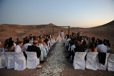 Couple toasting champagne after a successful agafay desert proposal in marrakech. Sunset camel ride in agafay desert leading to a romantic marry me moment.